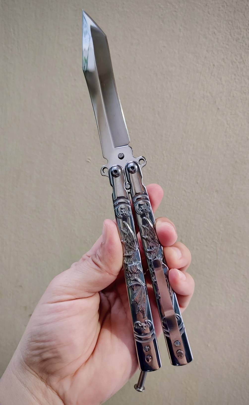 🦇 มีดควงค้างคาว เป็นบาลิซองสแตนเลส ขัดเงาเต็มตัว ใบทรงทันโตะ ปลายเฉียบ เส้นคมคมชัด ดูมีพลัง ด้ามแกะลายค้างคาวกางปีก รายละเอียดสวย งานนูนคมจนสัมผัสได้ ทั้งใบและด้ามเป็นสแตนเลส แข็งแรง จับแล้วรู้สึกถึงน้ำหนักพอดีมือ สายสะสม / สายชอบงานเงา / สายเท่เร