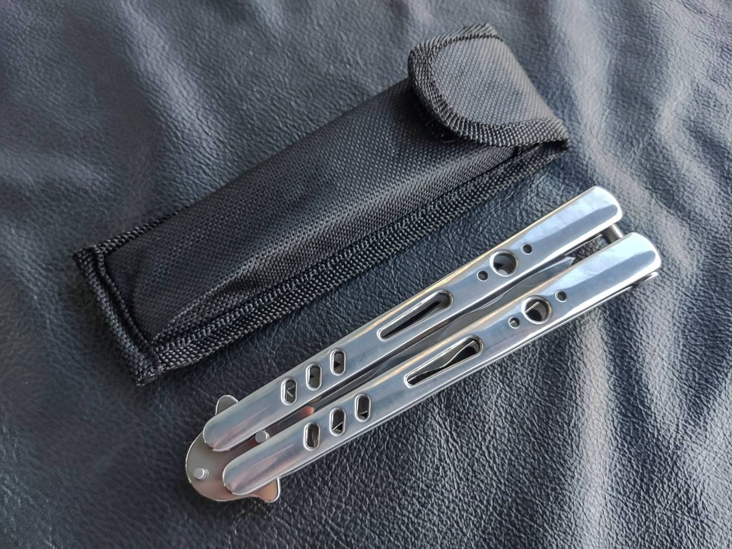 มีดบาลีซอง TK Tech มีดบาลิซองสไตล์เอเชีย ใบมีดเป็นทรงกริชสีเงิน ด้ามจับเป็นสแตนเลสฉลุลายสีเงินวาววับ จุดเด่นอยู่ที่ท้ายด้ามจับมีระบบสปริงแร็พ ทำให้หมุดล็อคด้ามไม่แกว่งไปมาในขณะเล่น จึงทำให้มิติของการควงสมดุล มาพร้อมซองไนล่อน