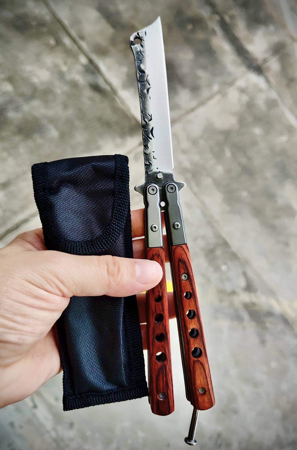 มีดควงบาลิซอง ทรงใบคัตติ้งปลายเฉียบ ไล่ลวดลายผิวใบแบบตีผิวดิบ ดูมีเอกลักษณ์ ด้ามผสมสแตนเลส + ไม้ ให้ฟีลแข็งแรงแต่ยังจับสบายมือ ตัวด้ามจับแน่น ไม่คลอนง่าย มีน๊อตยึดอย่างดี เวลาหมุนแล้วคุมจังหวะได้ดี น้ำหนักสมดุล ขนาดพอดีมือ ใช้โชว์ก็เท่ห์ ใช้งานก็ลงตัว